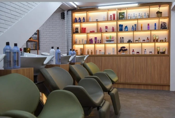 Área de lavatório do Ka Bareicha em São Paulo, com cadeiras confortáveis e prateleira iluminada com produtos de beleza premium